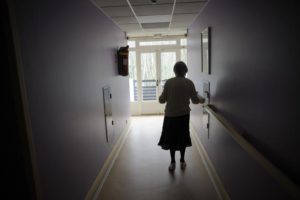 Elderly person walking in unlit corridor